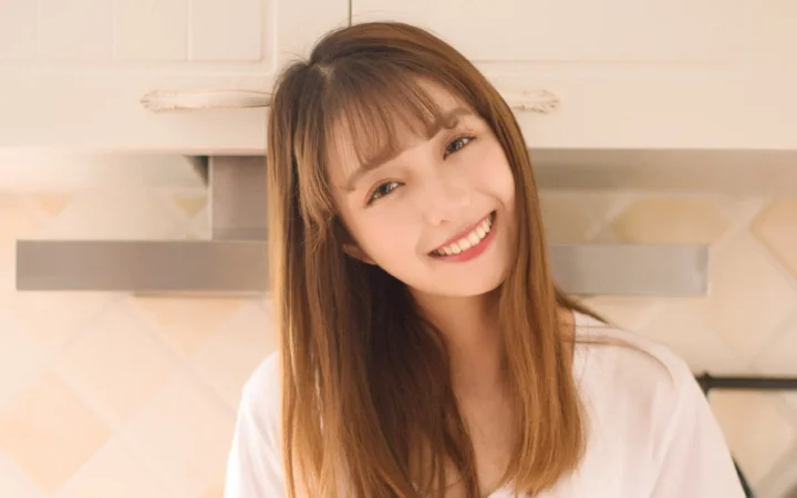 一位长发女性在室内面对镜头微笑。