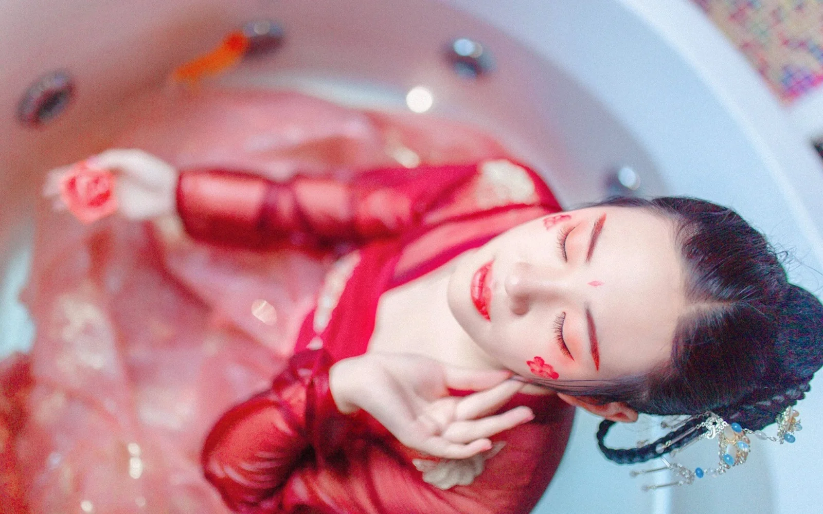 一名身穿红色传统服饰的女性闭着眼睛躺在浅色背景上。