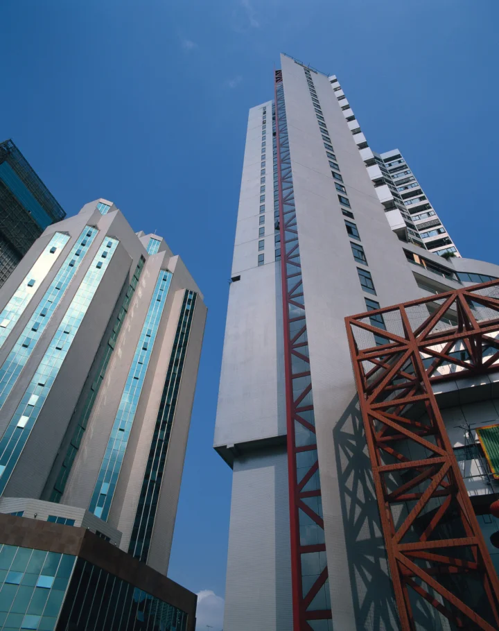 仰视视角展现蓝天下多座现代高层建筑及红色钢结构。