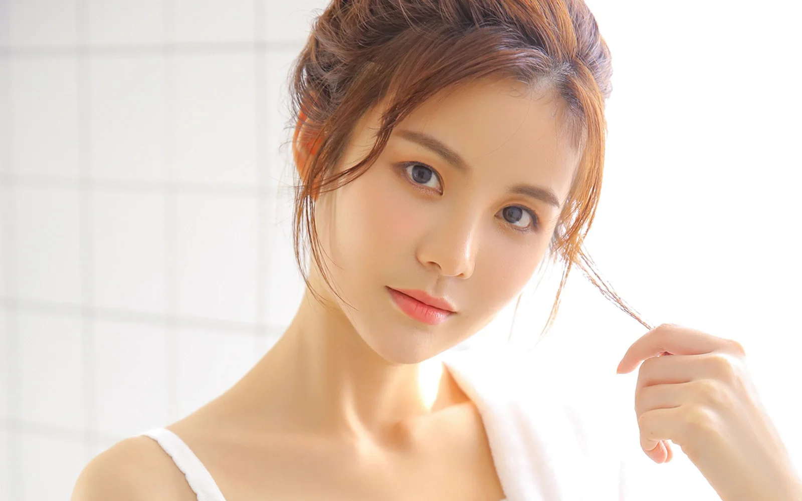 一位成年女性在明亮的窗前輕輕撥弄髮絲。