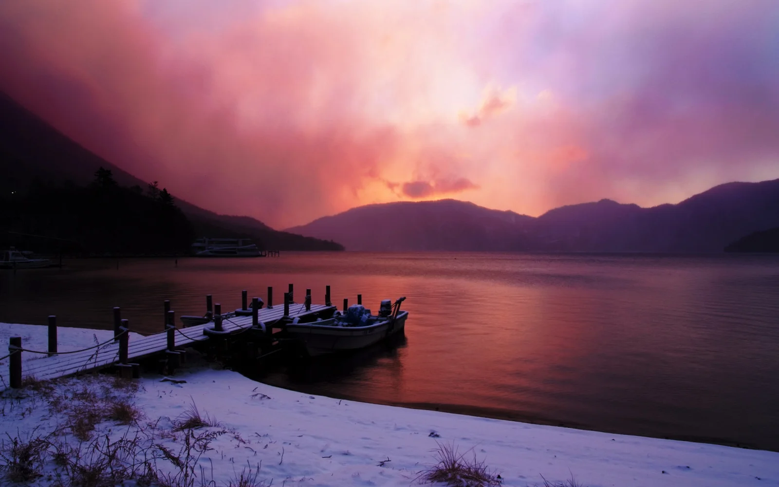 夕阳映照着湖面、远山、雪岸和停泊在码头旁的小船。