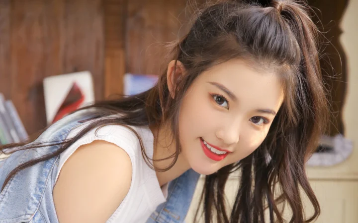 긴 머리의 여성이 실내에서 카메라를 바라보며 미소 짓는 근접 인물 사진이다.