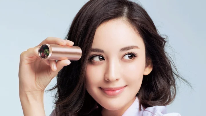 一名女性手持单筒望远镜，面带微笑注视前方。