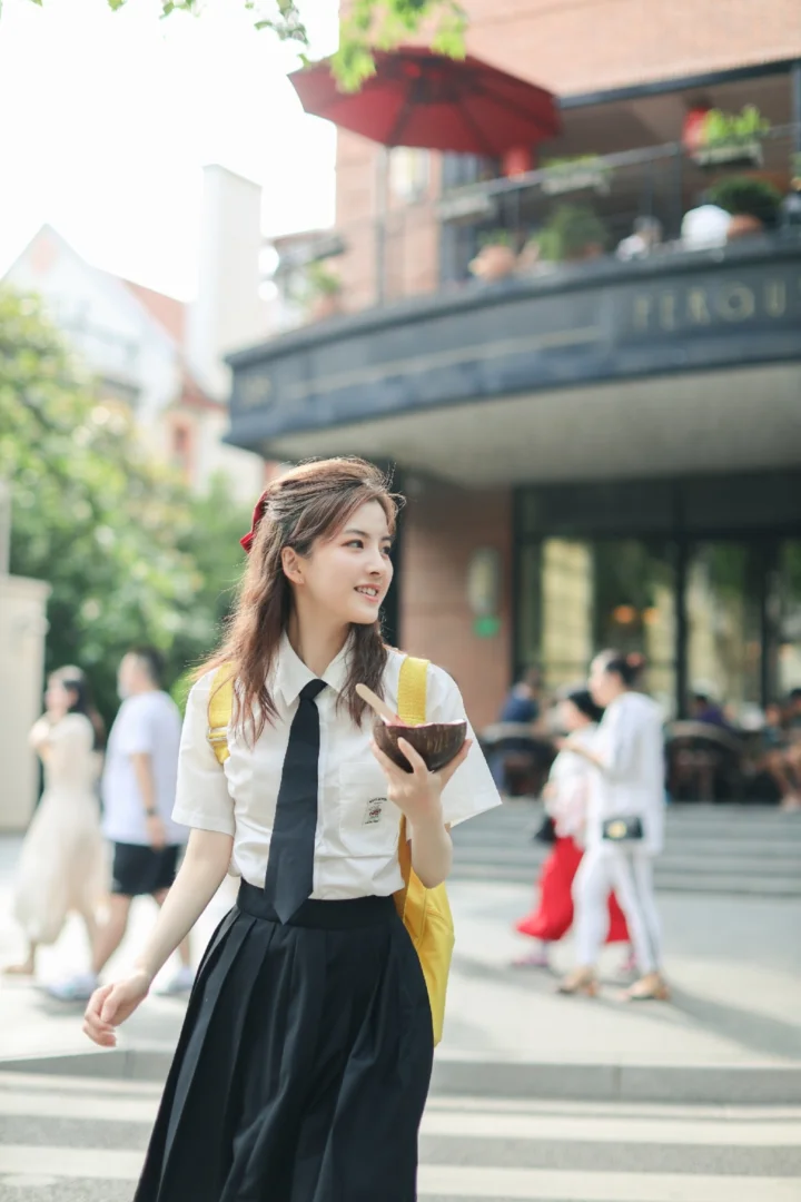 一名年轻女子穿着制服，手持手机站在城市街头。