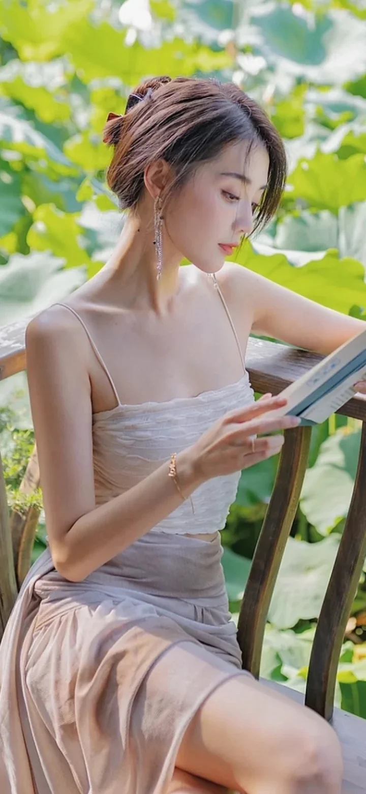 一位身穿浅色连衣裙的女性坐在绿意环绕的阳台上阅读。