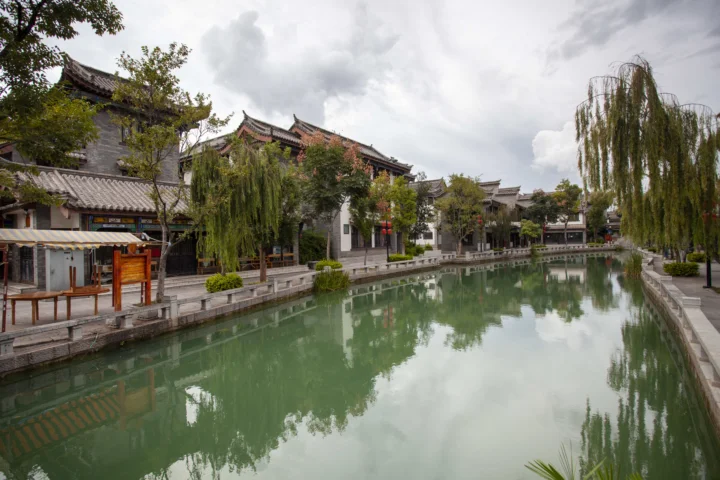 传统建筑、垂柳与水巷倒影构成宁静的城市景观。