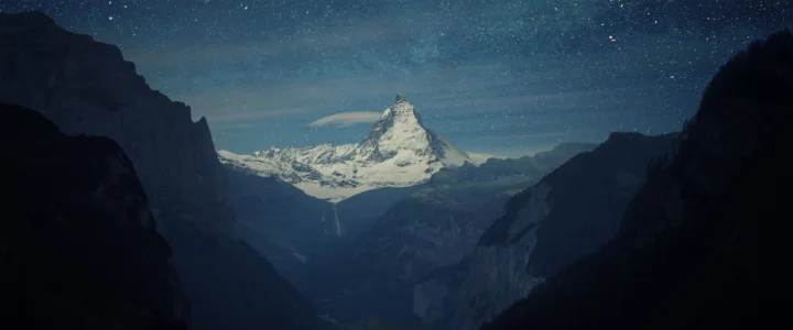 星空下，一座尖峭的雪山耸立在深邃山谷之间。