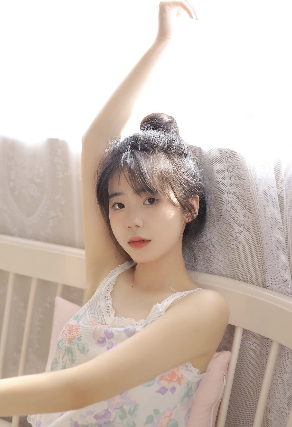 一名女性在室内靠坐，抬起一只手臂并面向镜头。
