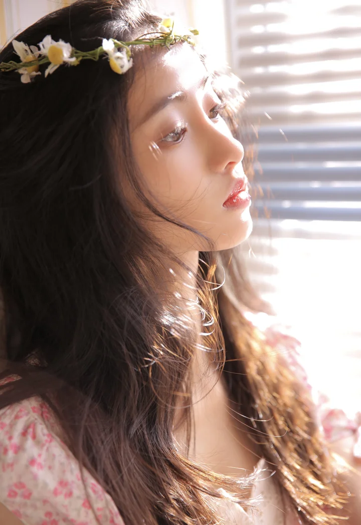 一位戴着花冠的长发女子在窗边柔和光线下侧脸凝望。