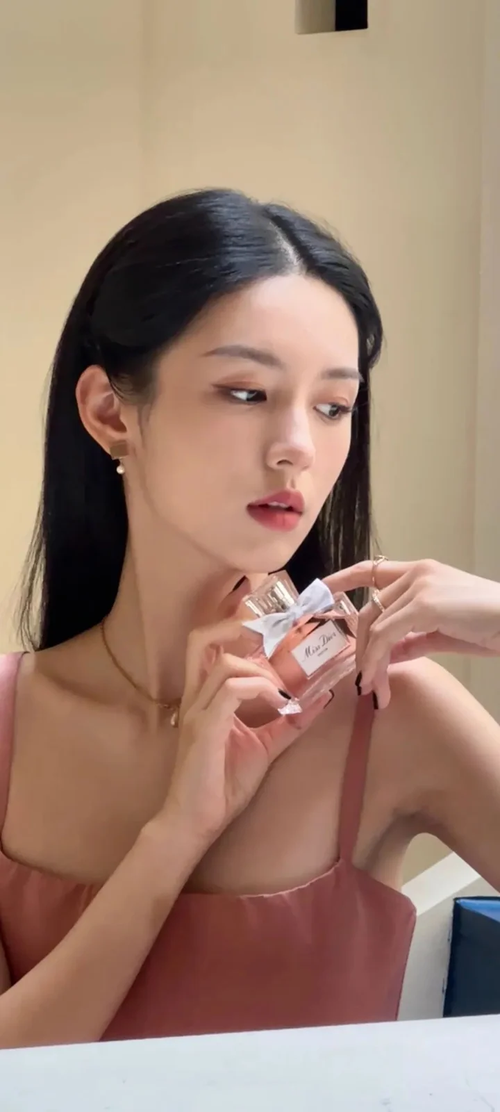一位成年女性在室内手持香水瓶的竖幅肖像照片。