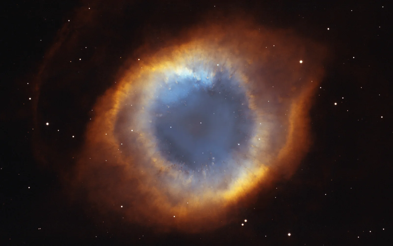深色星空背景中的蓝橙色环状星云，周围散布着明亮星点。