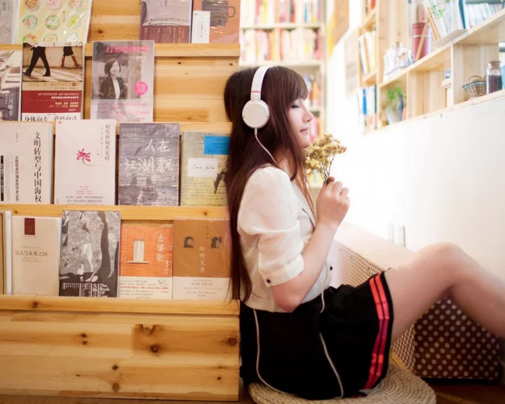 一名戴着耳机的女子坐在书架旁，手捧小束花朵。