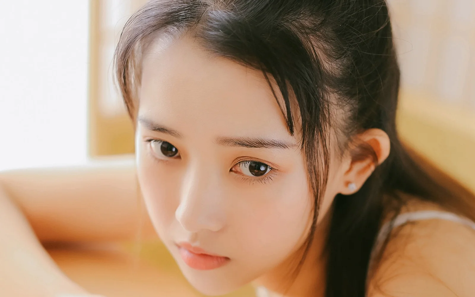 一位深色头发的女性在暖色光线下呈现近距离侧脸肖像。