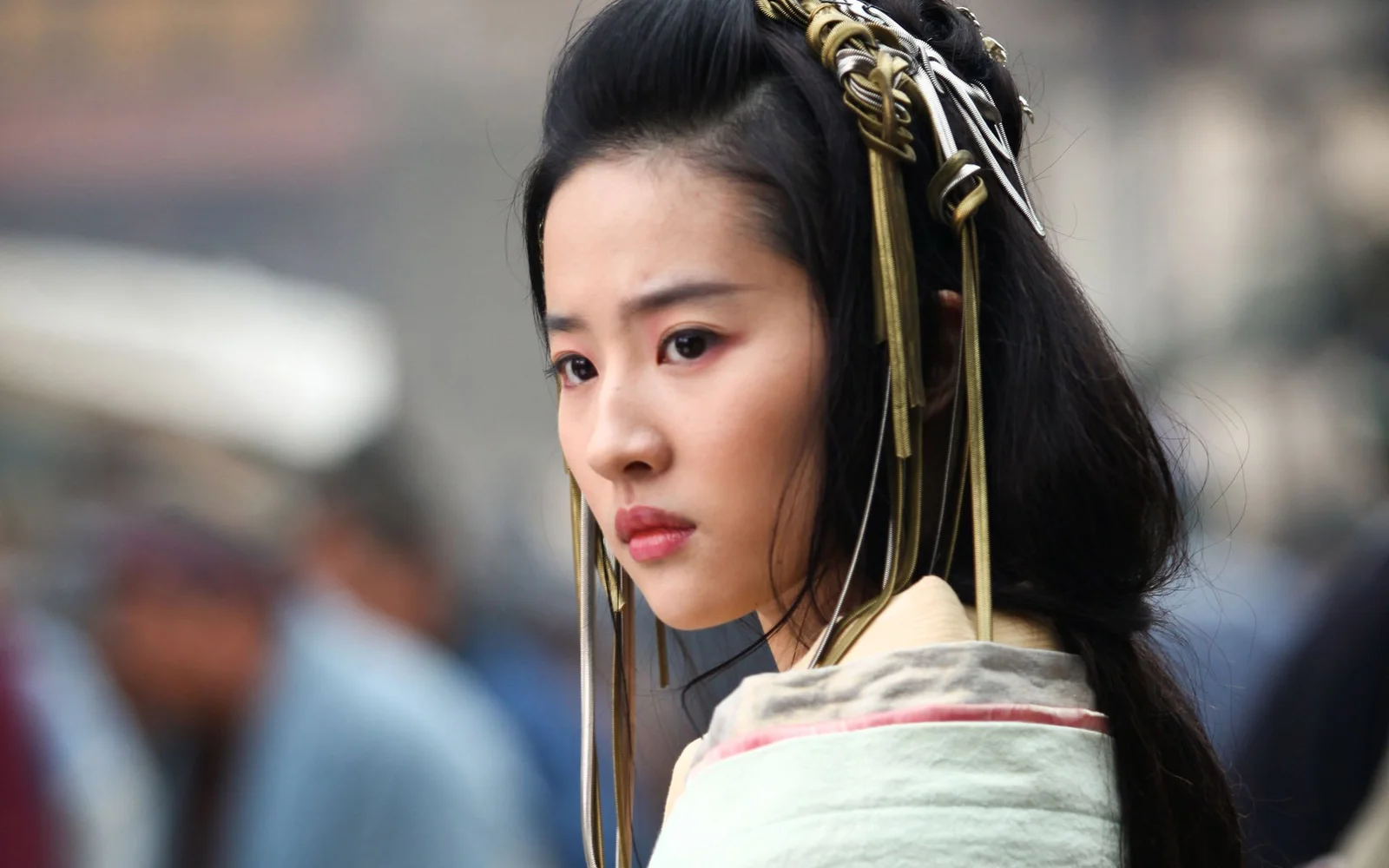 화려한 머리 장식을 한 여성이 부드럽게 흐려진 배경 앞에서 옆모습을 보이고 있습니다.
