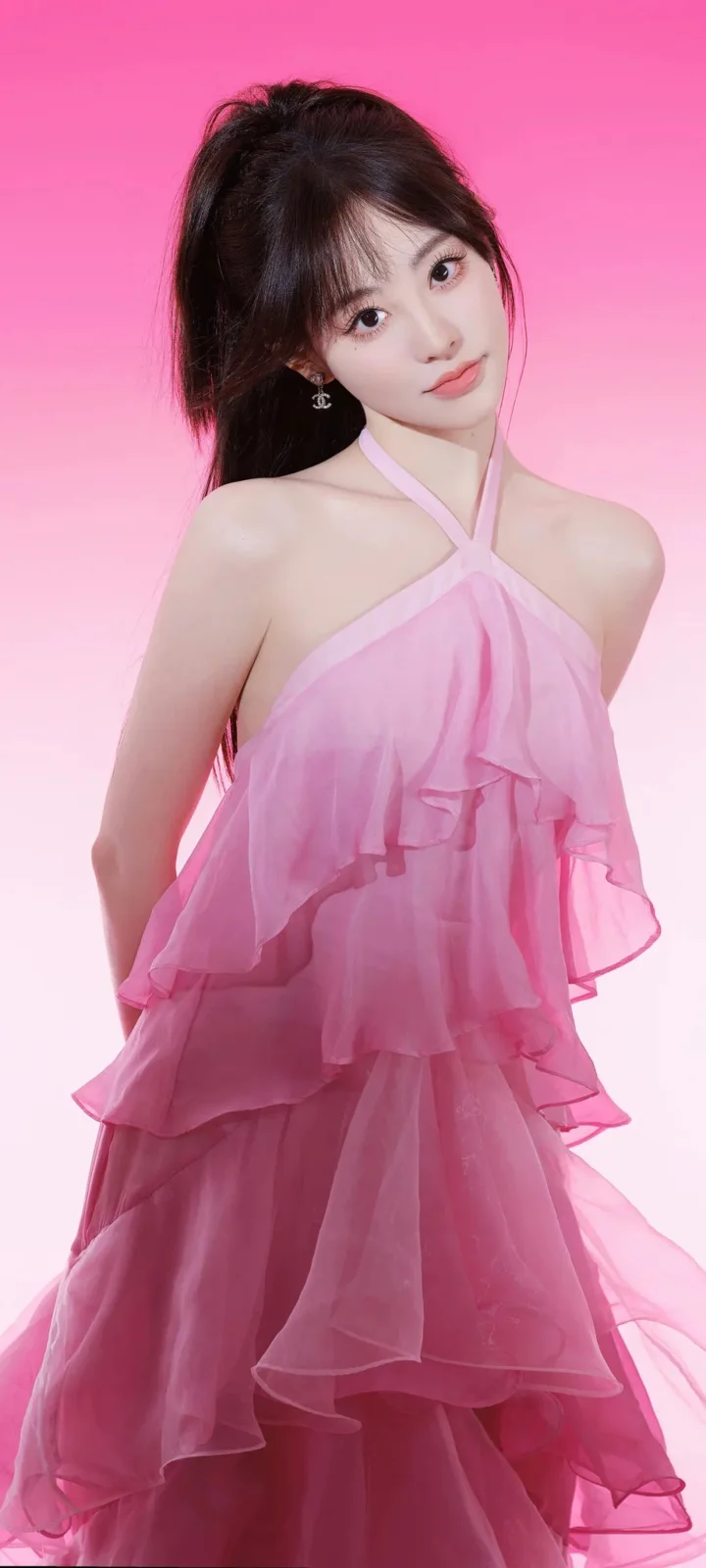 一位成年女性身穿粉色层叠礼服，在粉色背景前摆姿势。
