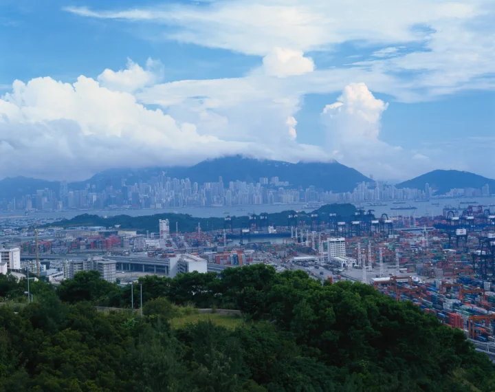 俯瞰繁忙的集装箱港口、城市天际线、远山和云层。