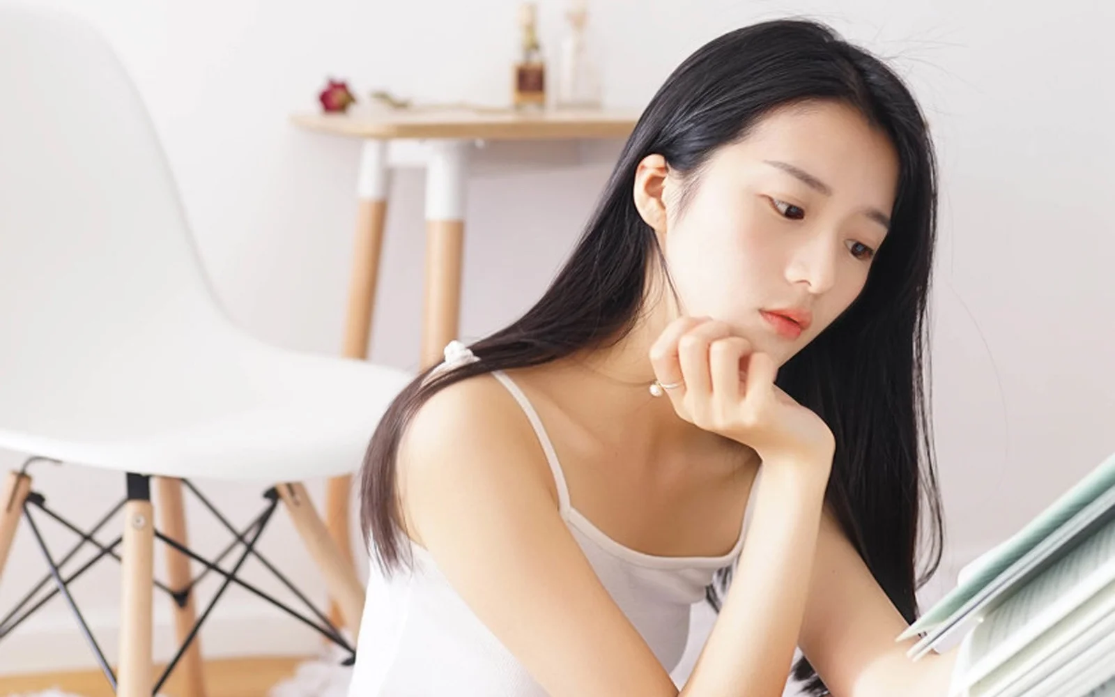 一名黑发女性在明亮的室内倚靠着手臂沉思。