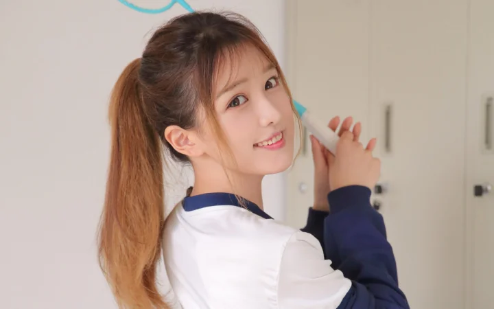 一名扎着马尾的女性在室内回头微笑。