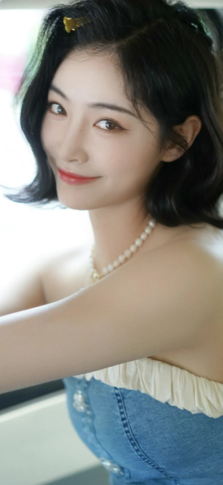 一位短发女子佩戴珍珠项链，面向镜头微笑。