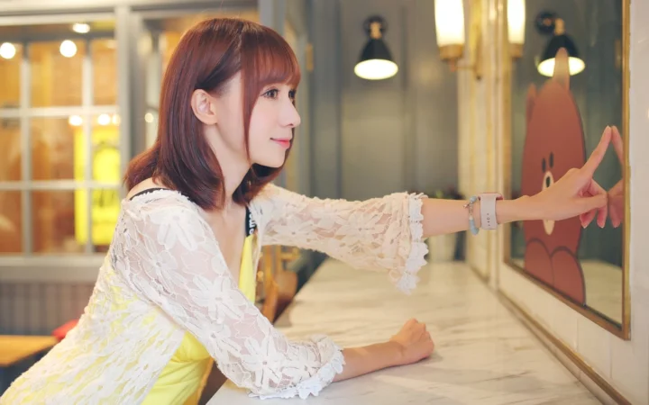 一名女性在室内靠近镜面伸手摆出姿势。