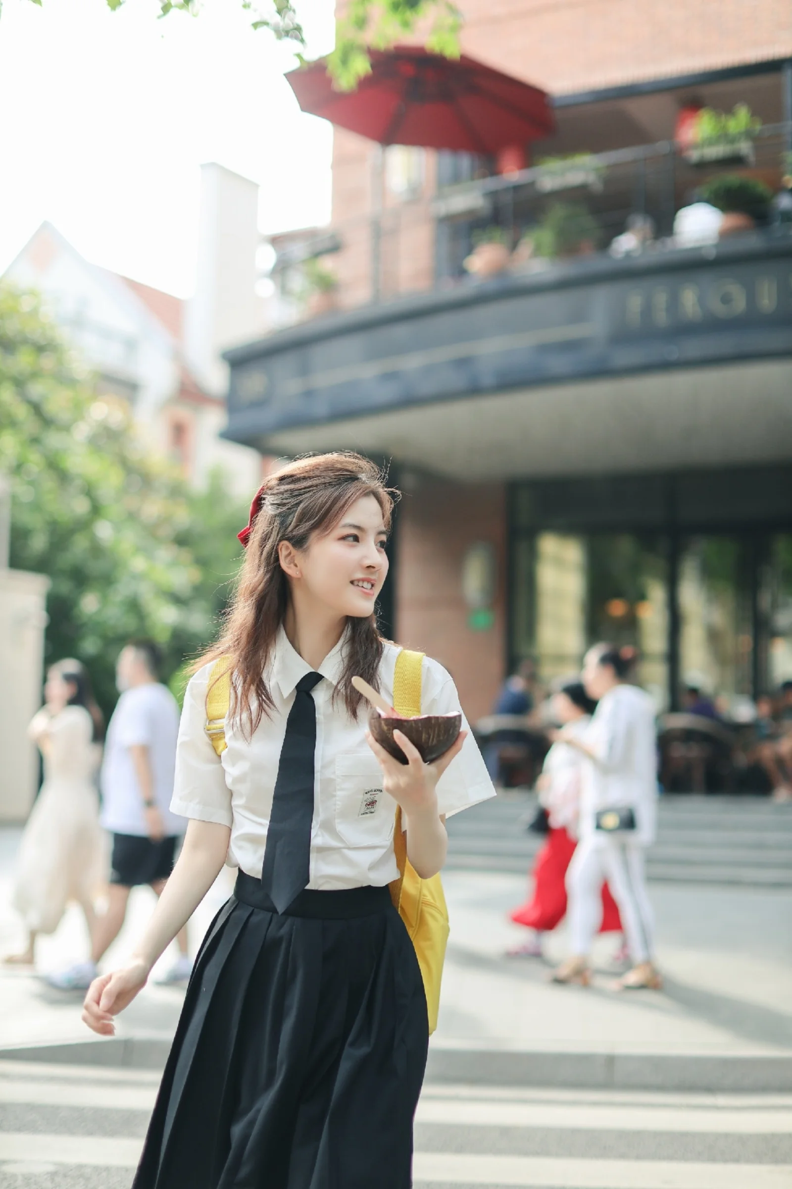 制服姿の若い女性がスマートフォンを手に街角に立っています。