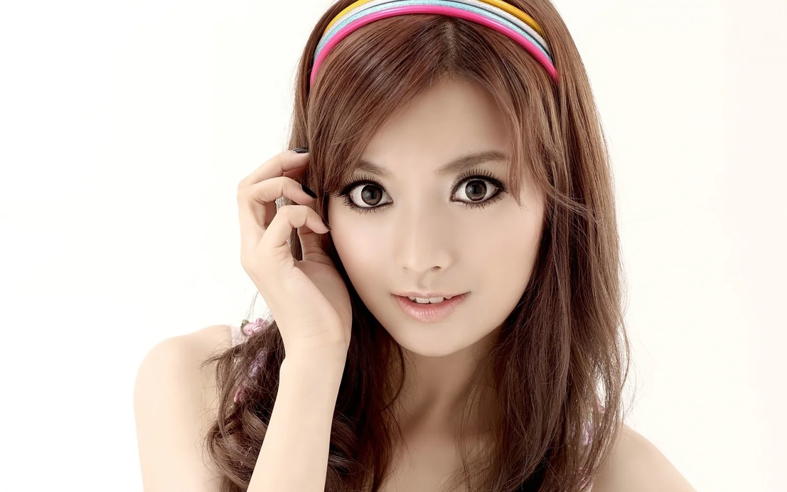 一名长发女性佩戴彩色发箍，面向镜头微笑，白色背景营造出明亮的棚拍肖像效果。
