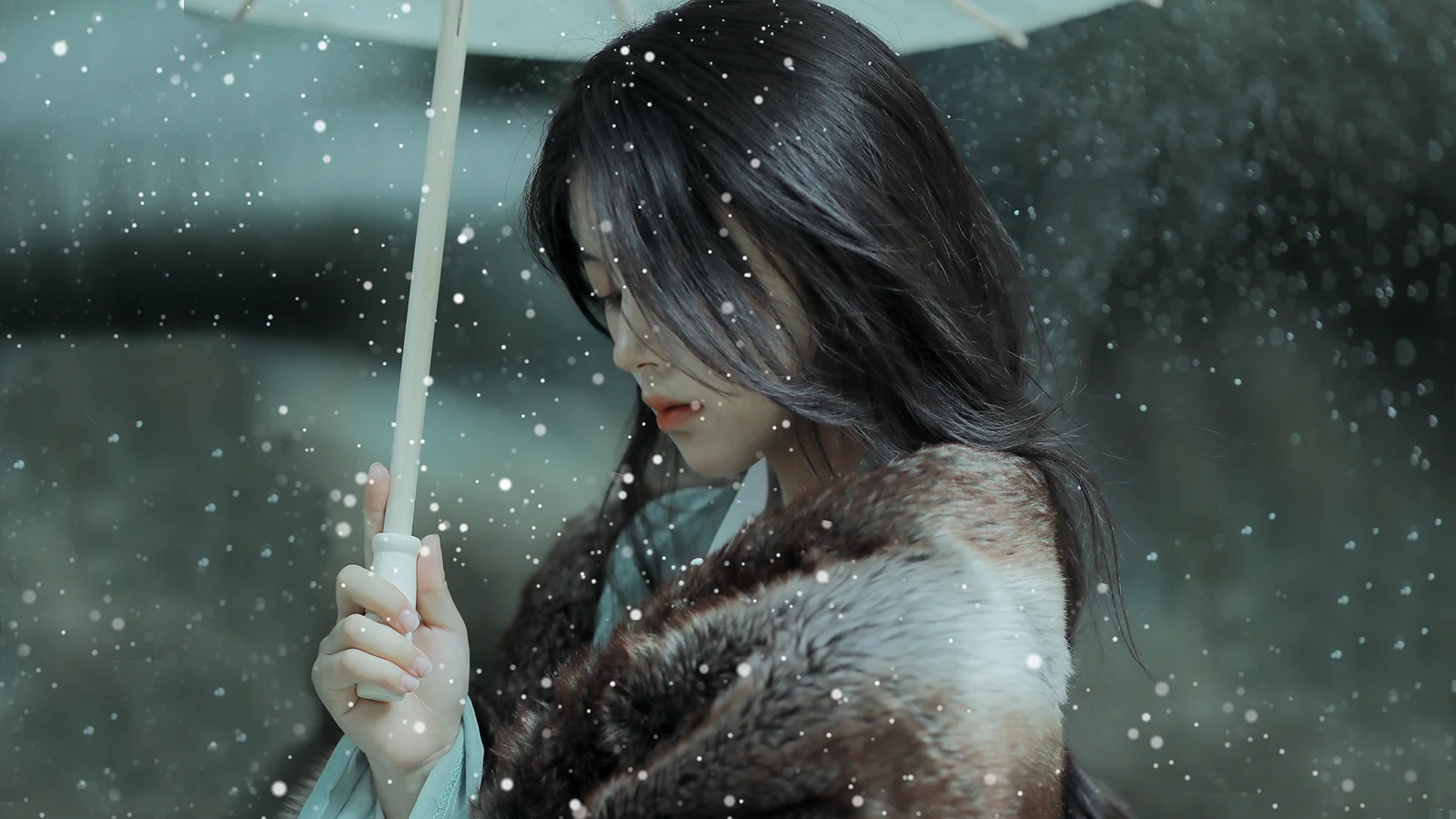 雨の中で女性が傘を差し、黒髪と濃い色のコートを雨粒が取り囲んでいる。