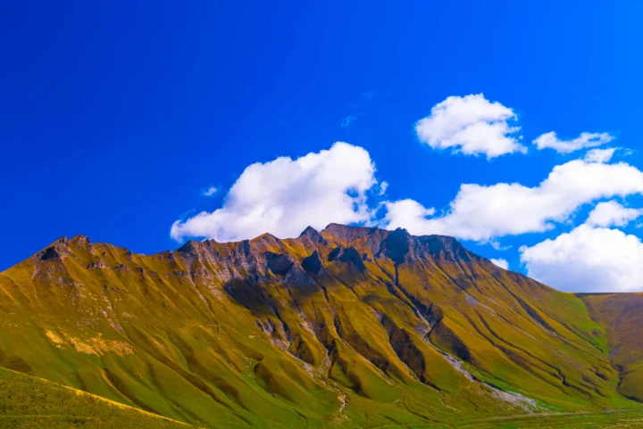 连绵的绿色山脉在湛蓝天空和白色云朵下延伸。