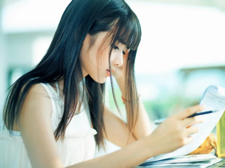 一名女子手持笔阅读纸张。