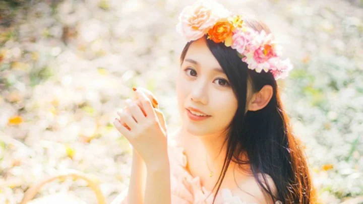 一位戴着花环的女子在明亮柔和的户外背景前微笑。