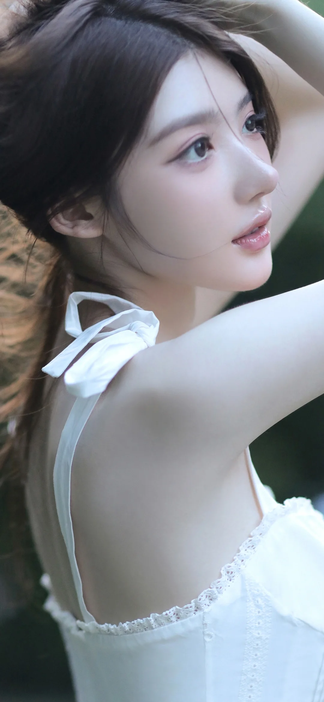 흰색 옷을 입은 성인 여성이 팔을 올린 채 옆모습을 보이고 있다.