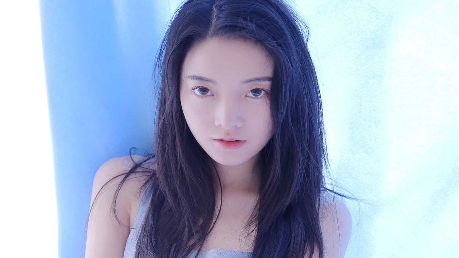 一位长发女性在蓝白色背景前面向镜头的肖像。