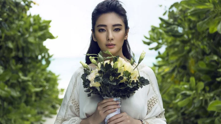 一名成年女性在绿意环绕的户外手捧花束。
