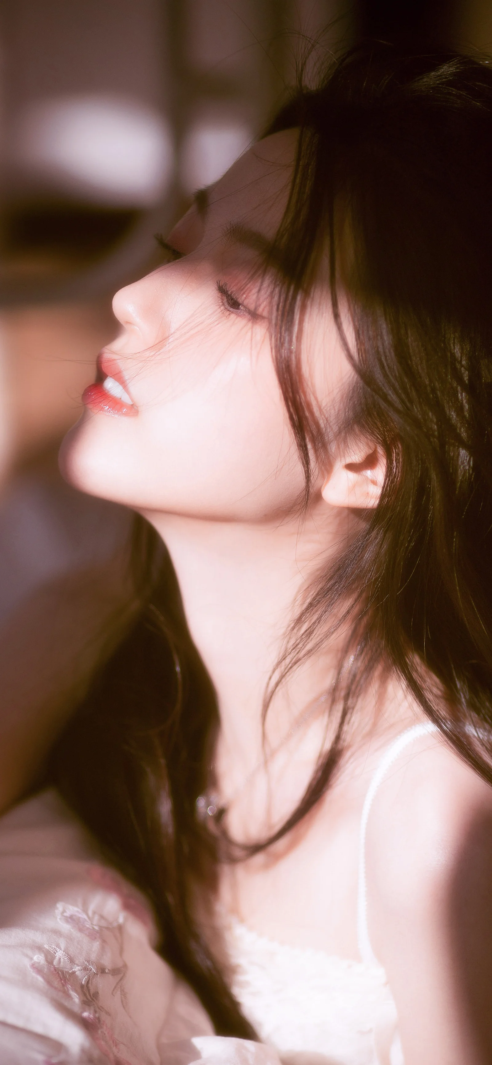 부드러운 빛 아래 검은 머리 여성의 옆얼굴과 목선, 어깨 윤곽을 담은 클로즈업 인물 사진이다.