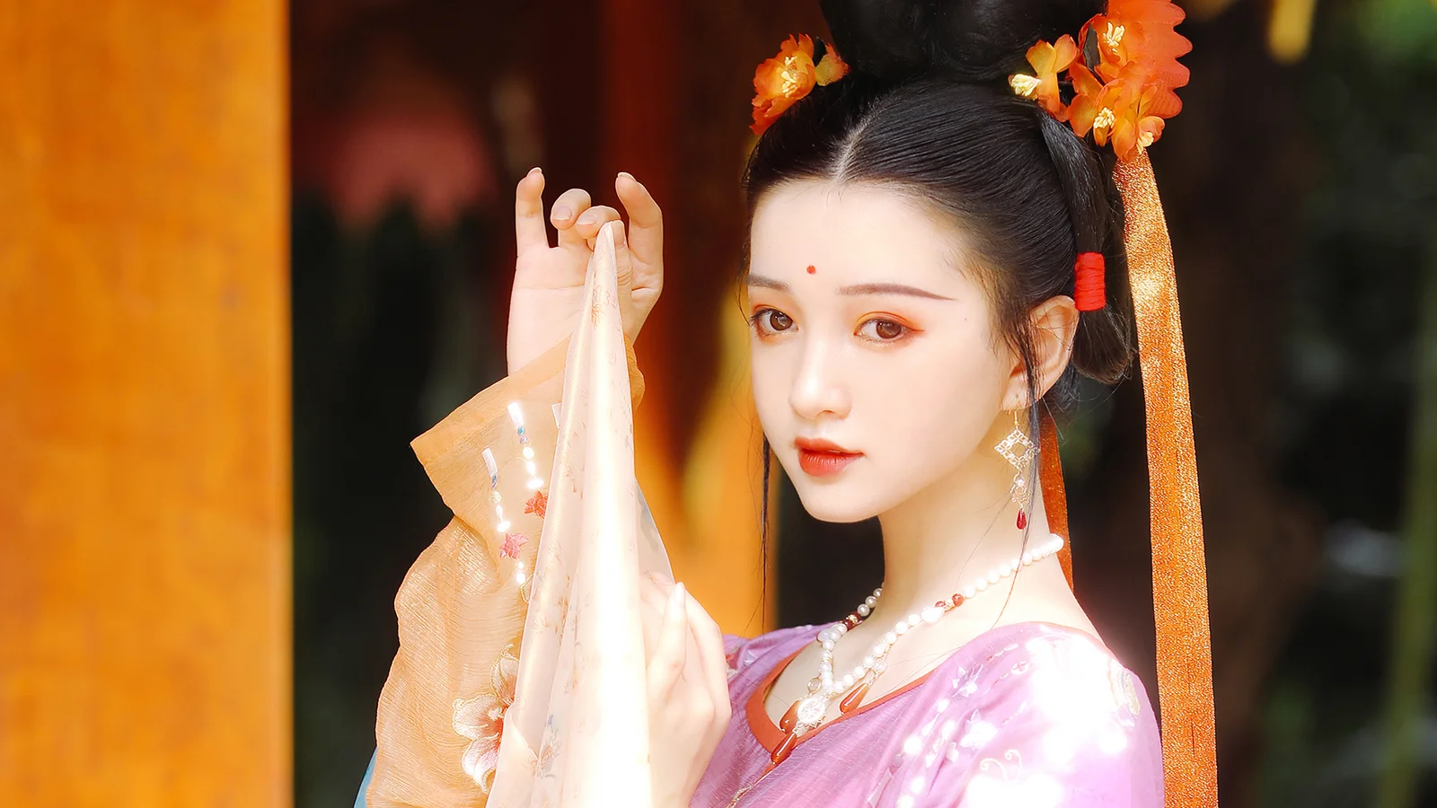 一位佩戴橙色发饰、身穿紫色传统服饰的女子站在门边。