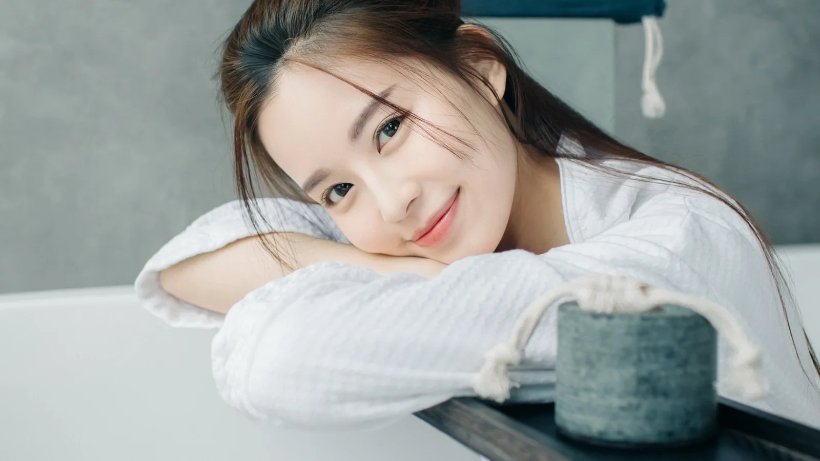 白い服を着た成人女性がテーブルに伏せ、カメラに向かって微笑んでいる。