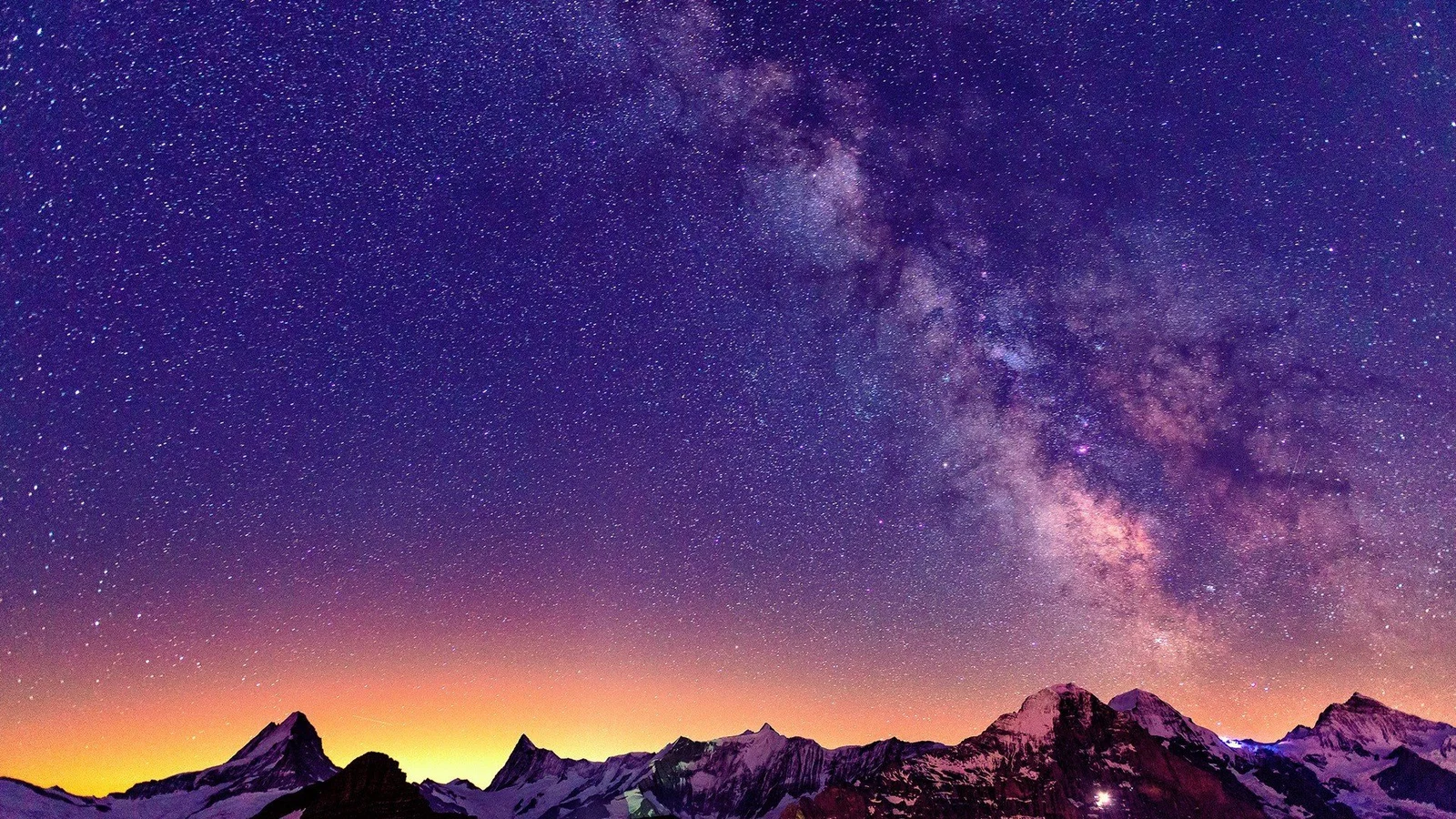 紫色银河横跨繁星密布的夜空，映照着暮色中的雪山群峰。