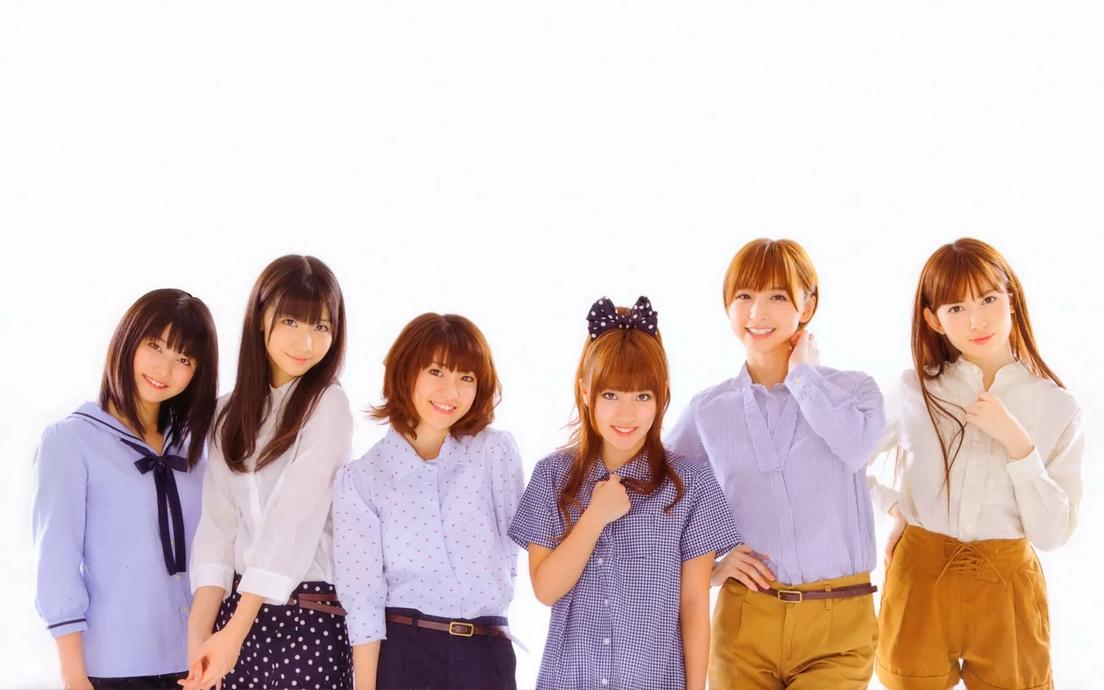 淡い色の服を着た6人の女性が白い背景の前に並んでポーズを取っています。