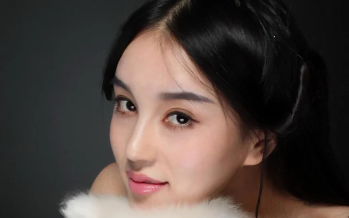 一位黑发女性在深色背景前的近距离肖像。