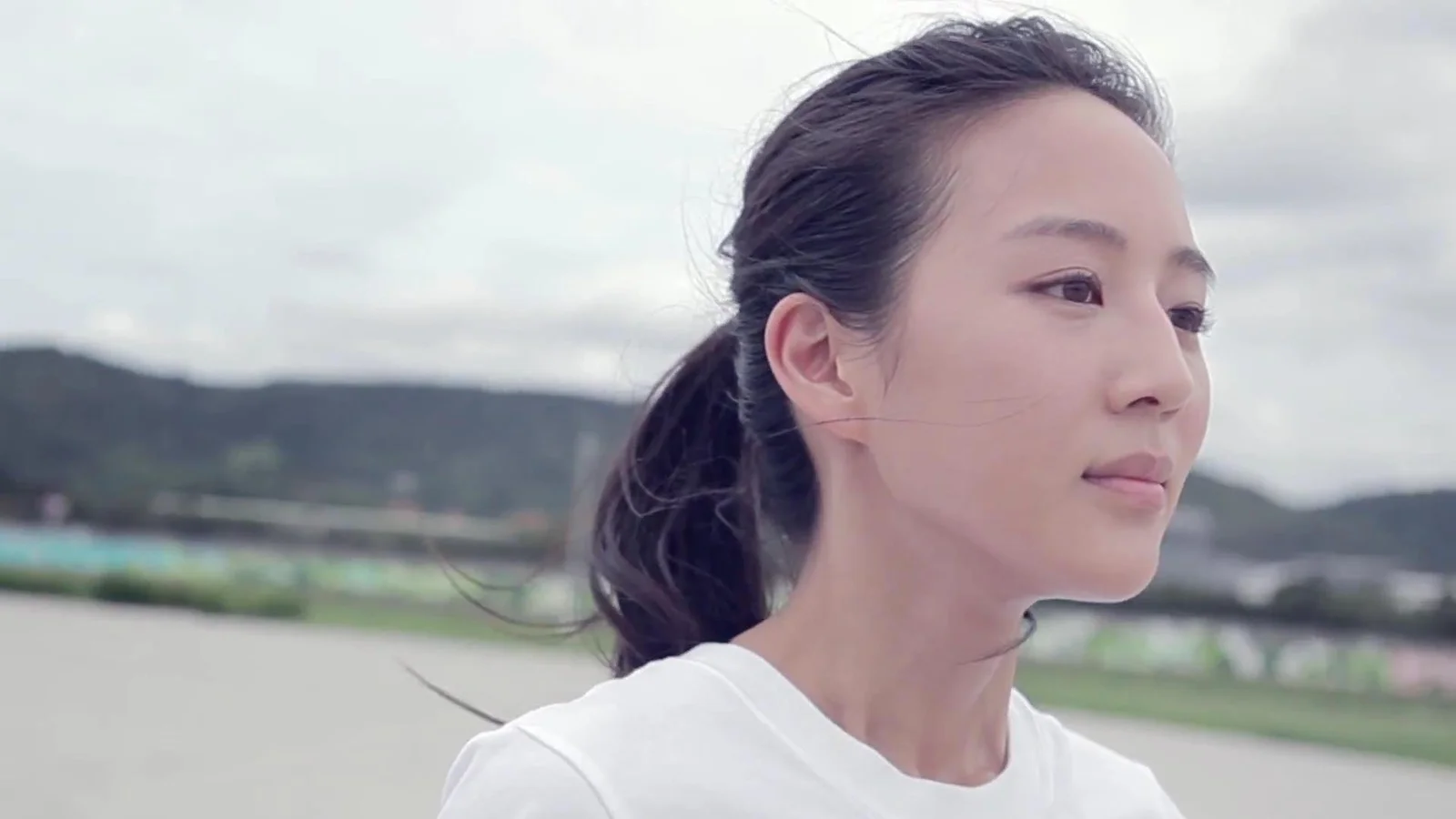 一名扎着马尾的女性在户外背景前的侧面近距离肖像。
