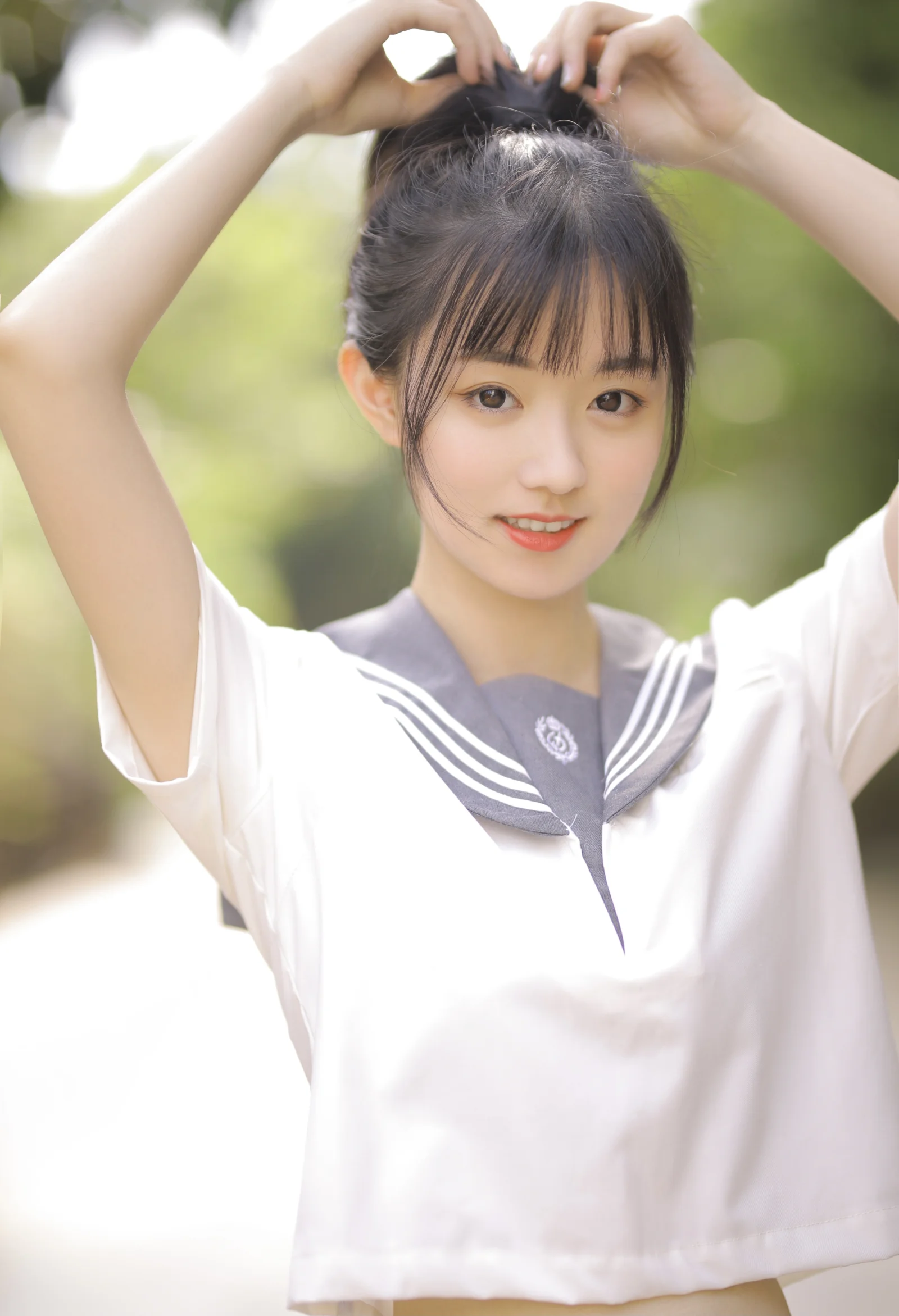 一名身穿水手服的女性在户外抬起双手整理头发。