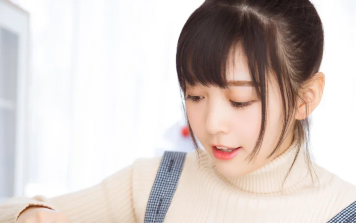 一位穿着奶油色高领毛衣的女性低头看向画面下方。