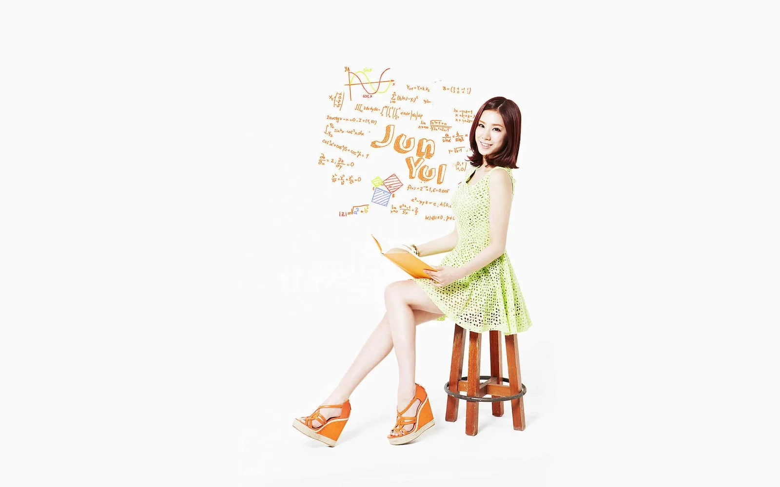 一名成年女性穿著淺綠色連身裙，坐在木凳上並手持一本書，背景為白色。
