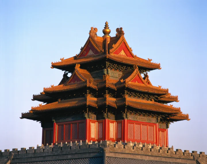 一座红墙金瓦的中式古建筑矗立在蓝天下。