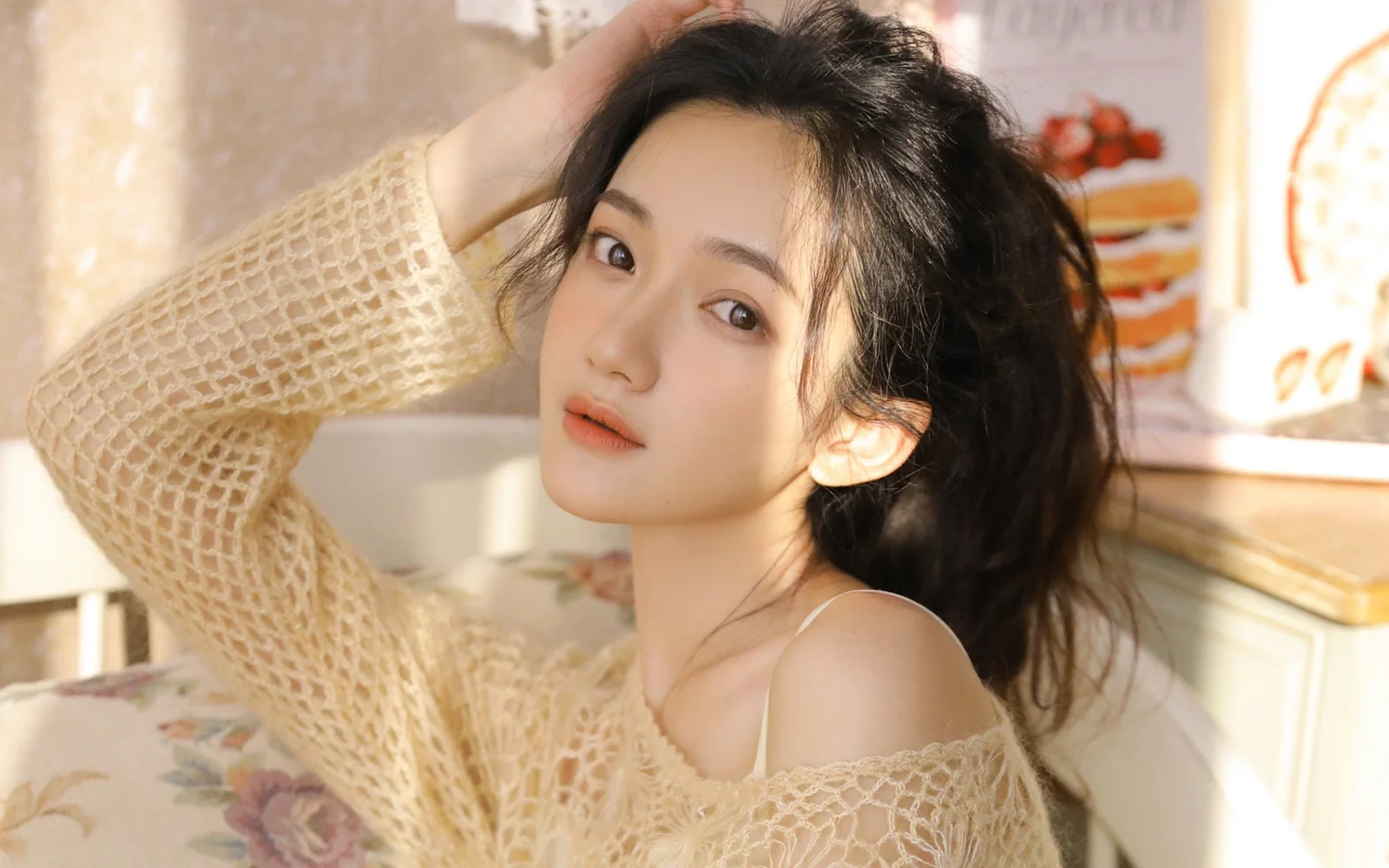 一名成年女性在室內暖色光線下靠近鏡頭擺姿勢。