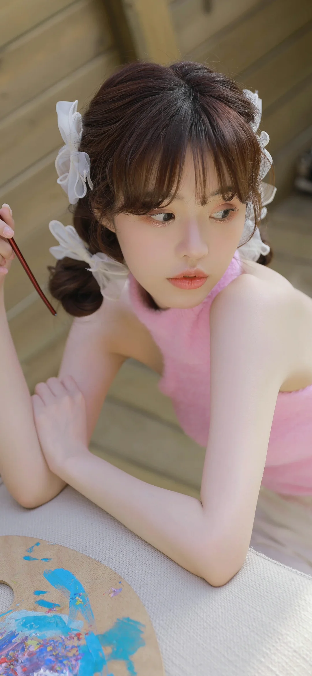 一名身穿粉色服装的女性俯身靠在室内织物表面上。