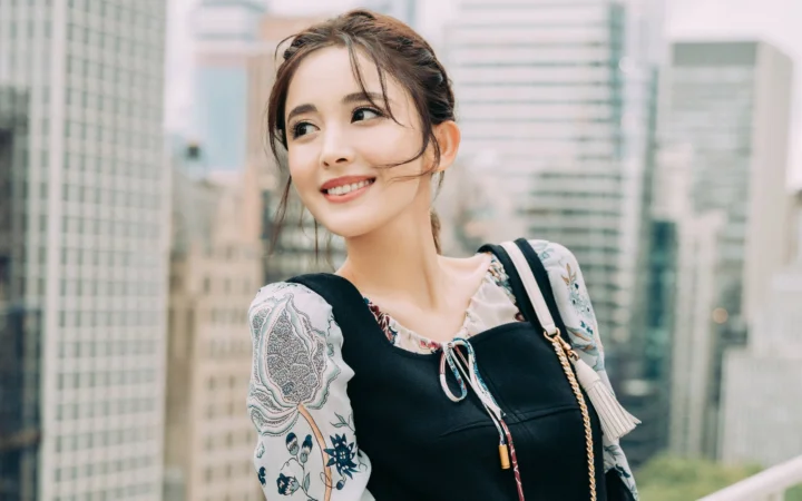 一名成年女性在城市高楼背景前微笑。