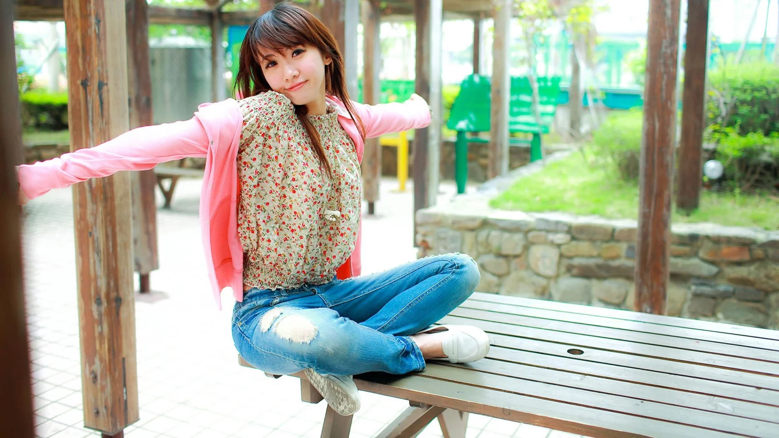 一名女子坐在户外木质长椅上张开双臂。