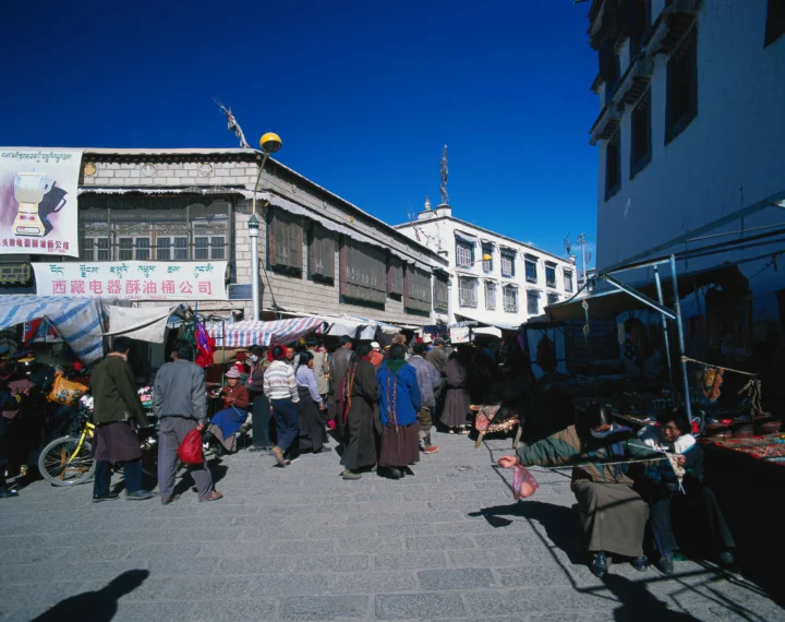 蓝天下的街市中，人们在传统建筑和摊位之间穿行。