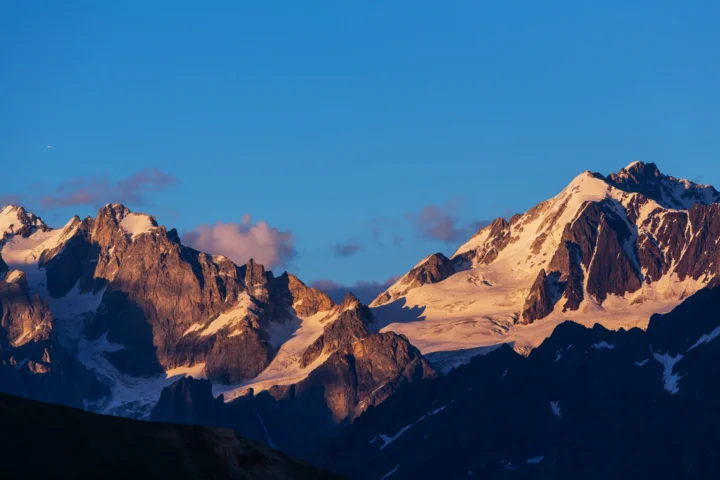 夕阳照亮了蓝天下的壮丽雪山群峰。
